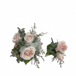 Two pale pink rose boutonnieres with greenery and ribbon