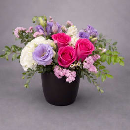 Pink and lavender roses arranged in a black vase