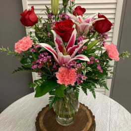 Bouquet of red roses, pink lilies, and carnations in a glass vase