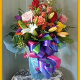 Colorful bouquet with roses, lilies, and a large ribbon in a vase