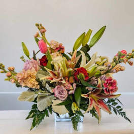 Mixed bouquet in a clear glass vase with lilies, roses, and pink blooms