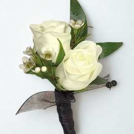 White rose boutonniere with small white blossoms and dark ribbon wrap