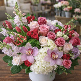 Mixed pink, red, and white floral arrangement in a white vase