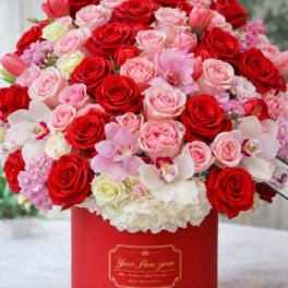 Red and pink roses with orchids in a red hat box