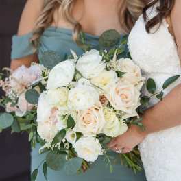 Bride and bridesmaid holding white and blush rose bouquets