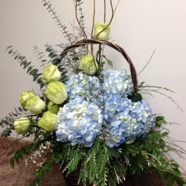 Basket arrangement with blue hydrangeas and pale green roses