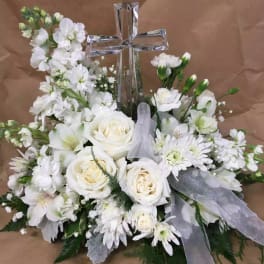 White floral arrangement with a clear cross centerpiece and sheer ribbon