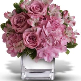 Pink roses and alstroemeria arranged in a clear square vase