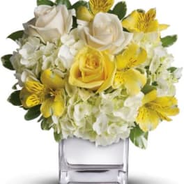 Yellow and white bouquet in a clear square vase