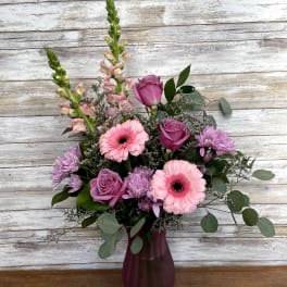 Pink and purple mixed flower arrangement in a burgundy vase