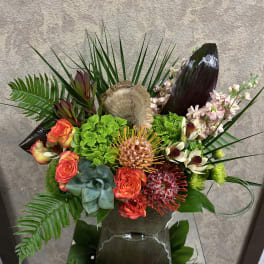 Tropical floral arrangement with orange roses and green hydrangea in a vase