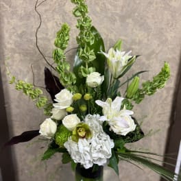 Tall white and green floral arrangement in a glass vase