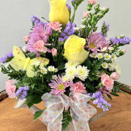 Mixed bouquet with yellow roses, pink daisies, and a polka-dot ribbon in a basket