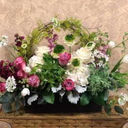 Mixed floral arrangement with pink and white roses in a low black container