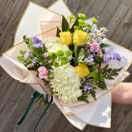 Hand-tied bouquet of yellow roses, white hydrangea, and purple flowers