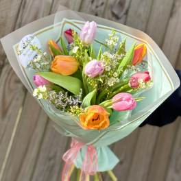 Bouquet of multicolored tulips wrapped in pale blue paper