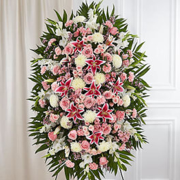 Standing spray of pink and white flowers on a black easel