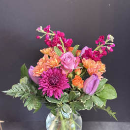 Mixed bouquet of pink, orange, and purple flowers in a glass vase