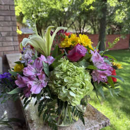 Mixed bouquet with lilies, hydrangea, roses, and daisies in a glass vase