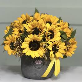 Bouquet of yellow sunflowers in a dark box with a yellow ribbon