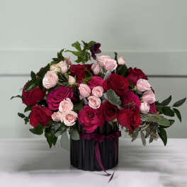Bouquet of red and pink roses in a black vase with ribbon