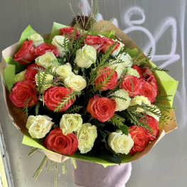 Bouquet of red and cream roses wrapped in brown and green paper
