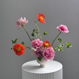 Pink and orange flowers arranged in a white vase