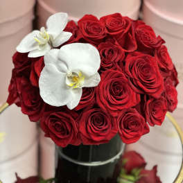 Red rose bouquet with two white orchids in a black vase