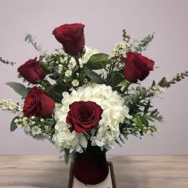 Red roses and white hydrangeas in a dark vase