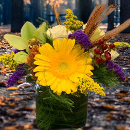 Yellow gerbera bouquet in a glass vase with purple accents