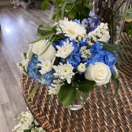Blue and white flower arrangement in a clear glass vase
