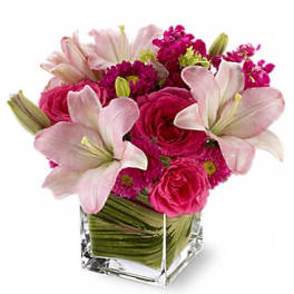 Pink lilies and roses in a clear square vase