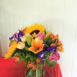 Colorful mixed bouquet in a glass vase with sunflowers and roses