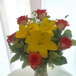 Bouquet of red roses and yellow lilies in a clear glass vase