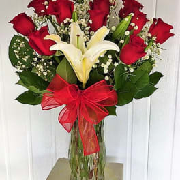 Bouquet of red roses and white lilies in a glass vase with a red bow