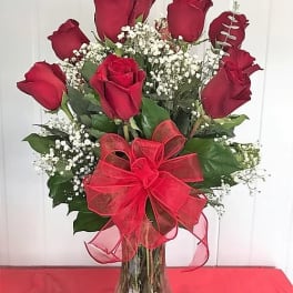 Red roses in a clear glass vase with a red bow
