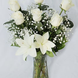 White roses and lilies arranged in a clear glass vase