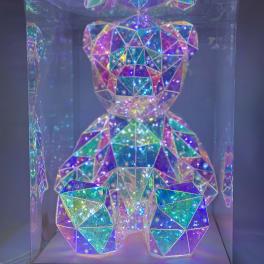 Iridescent geometric teddy bear figurine in a clear display box