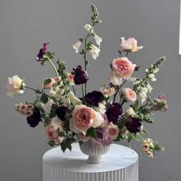 Mixed pink and purple floral arrangement in a white vase