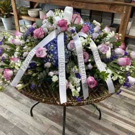 Large sympathy floral arrangement with pink and purple roses and white ribbons