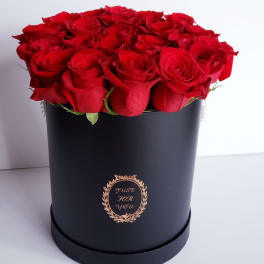 Red roses arranged in a black round box