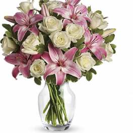 Pink lilies and white roses arranged in a clear glass vase