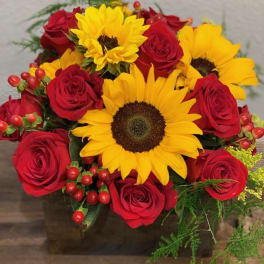 Bouquet of red roses and yellow sunflowers in a square vase