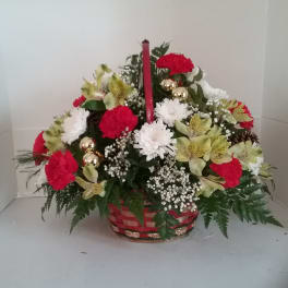 Basket arrangement of red and white flowers with a tall red candle