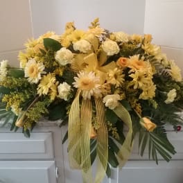 Yellow and white floral casket spray with ribbon