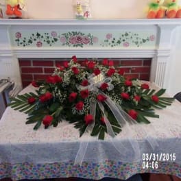 Large red rose arrangement on a table with a sheer ribbon bow