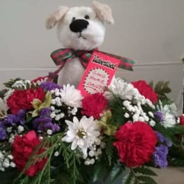 Stuffed dog above a colorful flower arrangement with a card