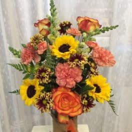 Bouquet of sunflowers, roses, and carnations in a glass vase