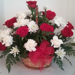 Basket arrangement of red roses and white daisies with a red bow