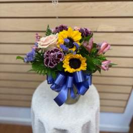 Mixed bouquet with sunflowers, roses, and alstroemeria tied with a blue ribbon